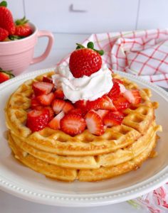 Stacked Waffles with fresh strawberries and whipped cream.