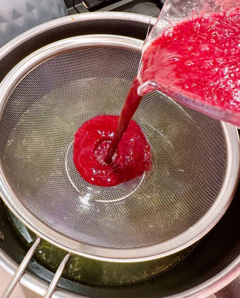 Straining berry mixture over lemon mixture.