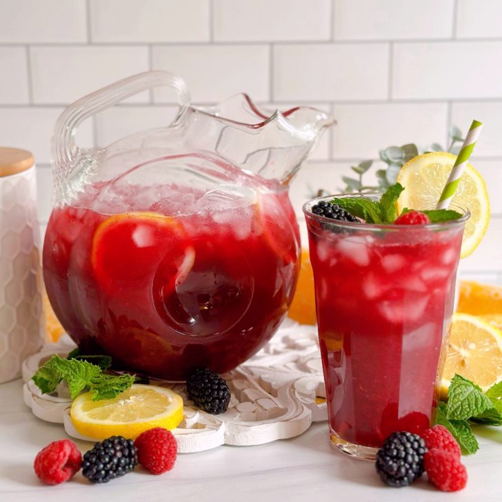 Triple Berry Lemonade in a beautiful pitcher with a tall glass of lemonade next to it.