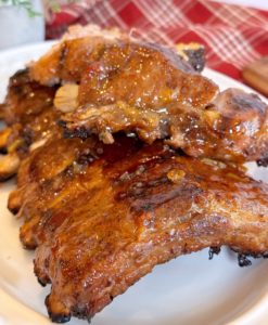 Rack of Baby Pork Ribs stacked on a platter with Apricot BBQ sauce.