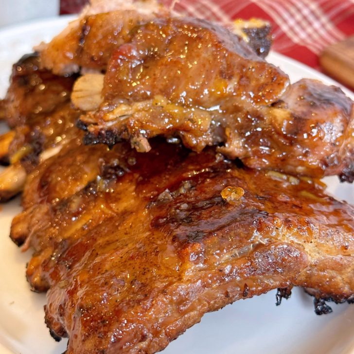 Rack of Baby Pork Ribs stacked on a platter with Apricot BBQ sauce.