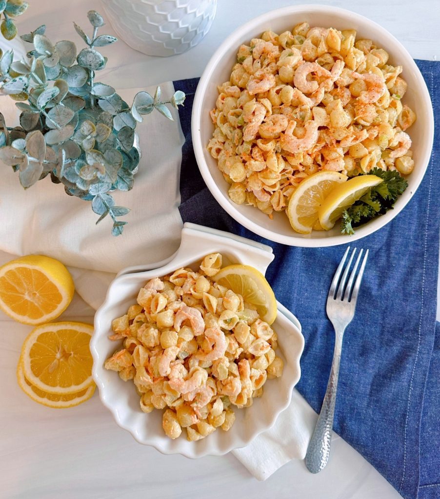 Shrimp Pasta Salad in a clamshell dish with fresh lemon slices.