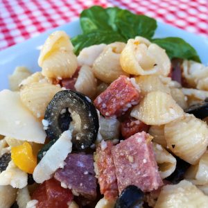 Bowl full of Antipasto pasta salad with fresh basil sprig