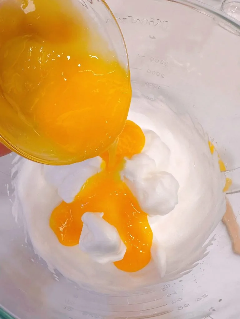 Adding egg yolks into whipped egg whites.