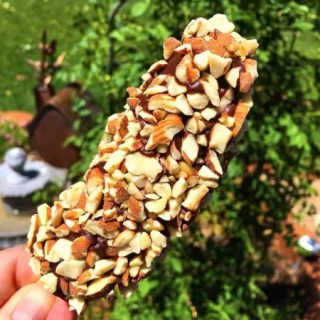 Holding a hand dipped frozen banana outside.