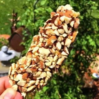 Holding a hand dipped frozen banana outside.