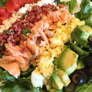 Plate filled with rows of delicious cobb salad toppings including delicious salmon