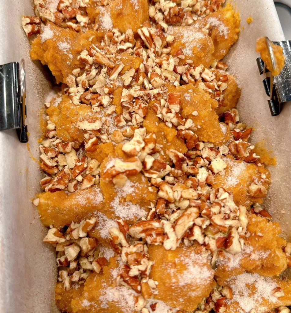 Final layer of pumpkin monkey bread sprinkled with sugar and nuts ready to bake.