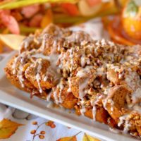 Pumpkin Spice Monkey Bread on a white plate with glaze.