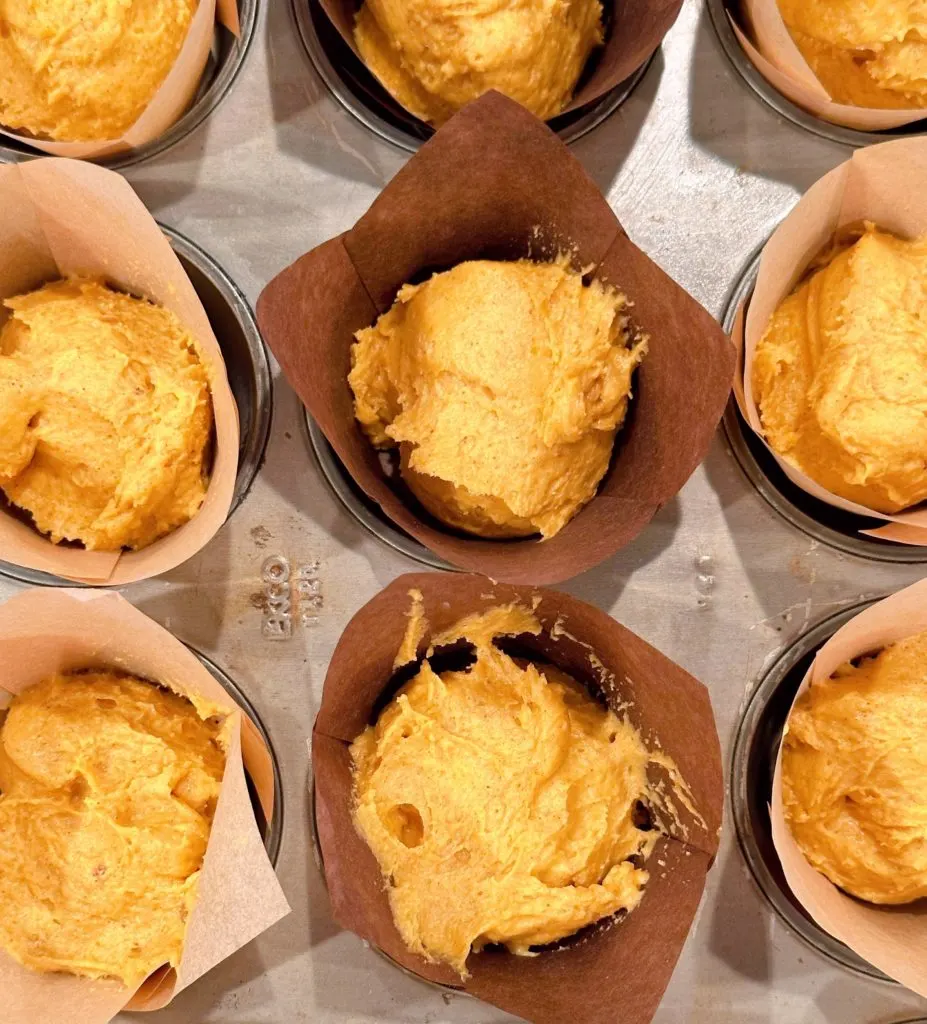 Filling the muffin tin with pumpkin batter. 