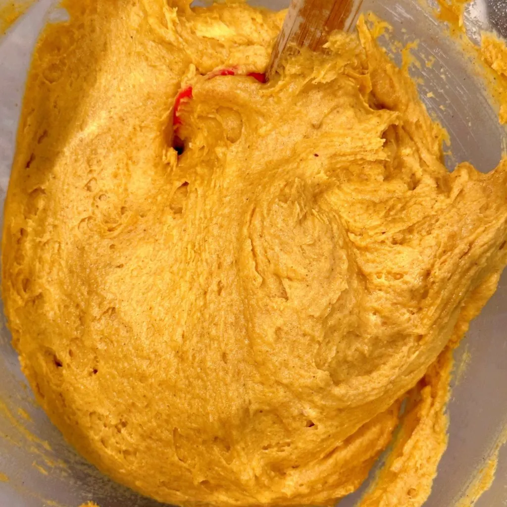 Pumpkin muffin batter mixed in a stand-mixer bowl.