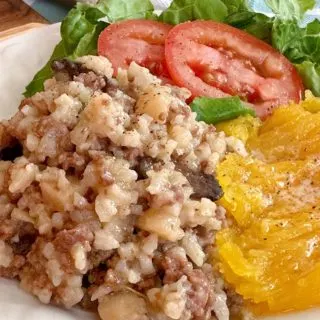 Dinner in a pumpkin filling and pumpkin with a side salad on a dinner plate.