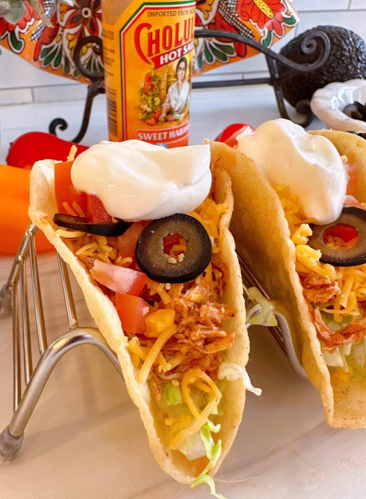 Chicken tacos with sour cream and all the toppings.