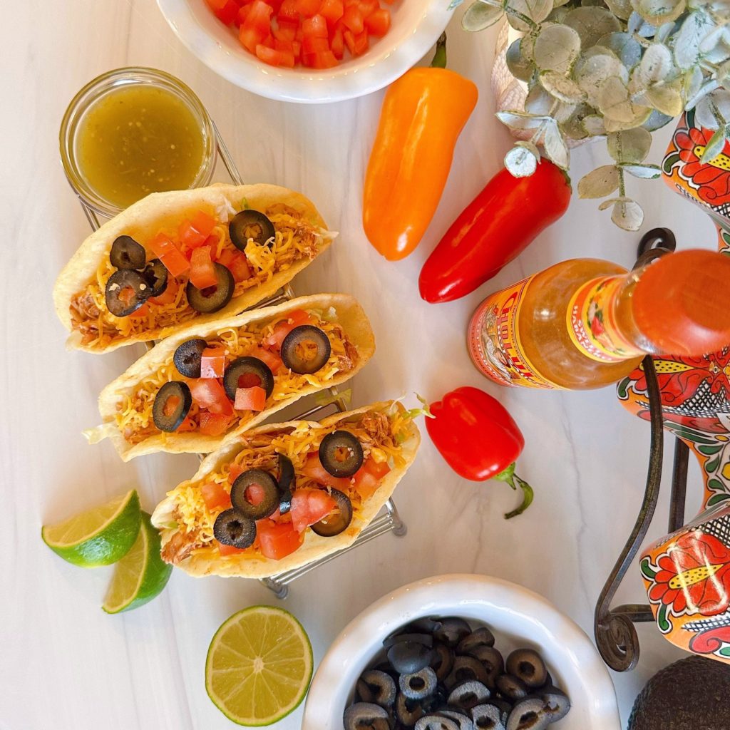 Crock Pot Chicken Tacos in a taco stand with all the toppings.