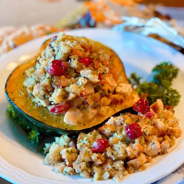 Bowl filled with a beautiful stuffed acorn squash and an extra side of stuffing.