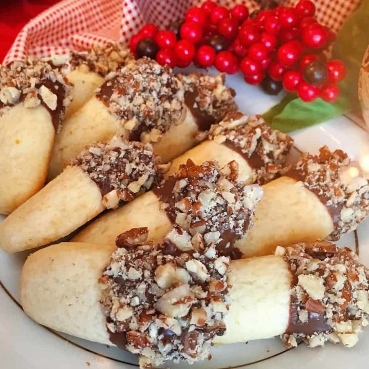 Plate full of chocolate Orange Log cookies dipped in chocolate and rolled in chopped nuts.