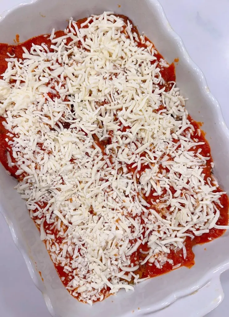 Chicken covered in marinara sauce and grated cheese.