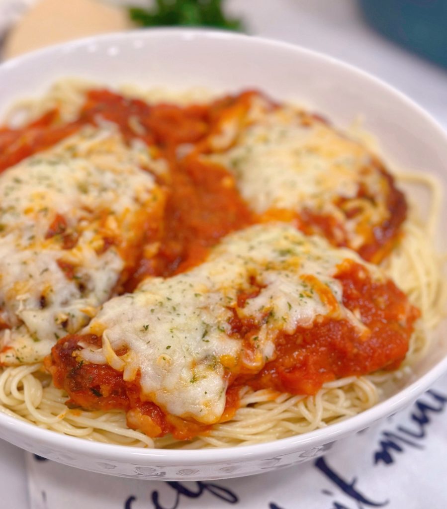 Chicken Parmesan on a bed of pasta, close-up.