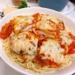 Huge bowl of Chicken Parmesan on top of a bed of Angel Hair Spaghetti.