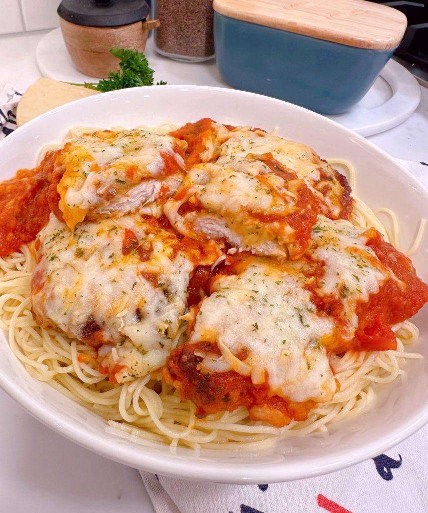 Chicken Parmesan piled high on a bed of spaghetti noodles.