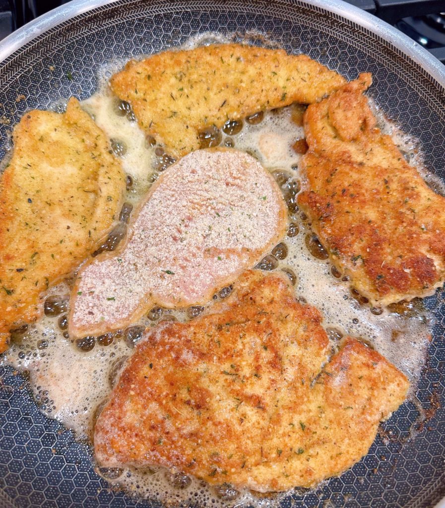 Turning chicken over in a large skillet.