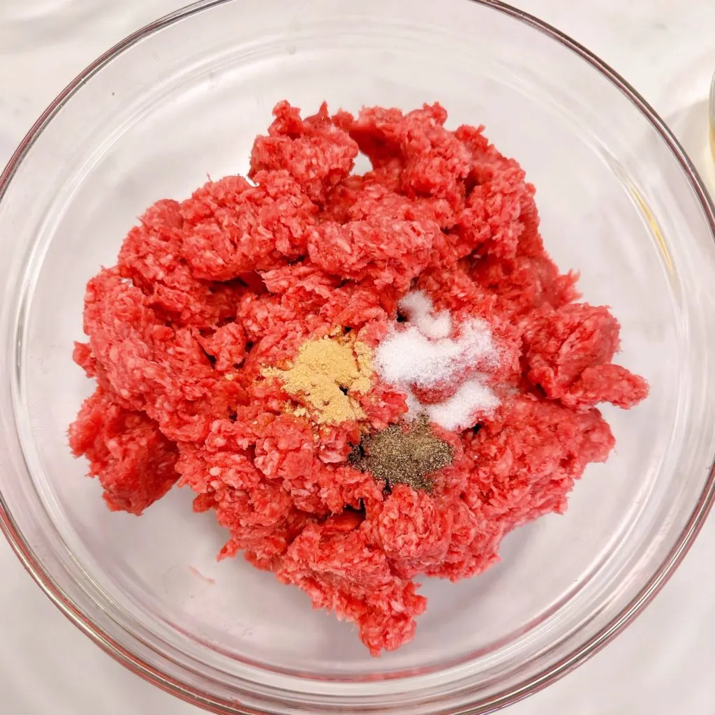 Ground beef in a bowl with seasonings.