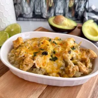 Bowl filled with rice and chicken chili verde on a wooden cutting board.