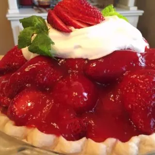 Close-up photo of Strawberry Pie with a dollop of whipped cream and mint