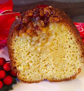 Rum Cake slice on a white plate with holiday berries surrounding it.