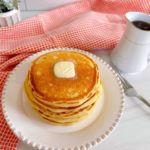 Stack of pancakes on a plate with a pat of butter.