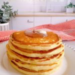 Stack of pancakes with syrup pouring over the top of them.