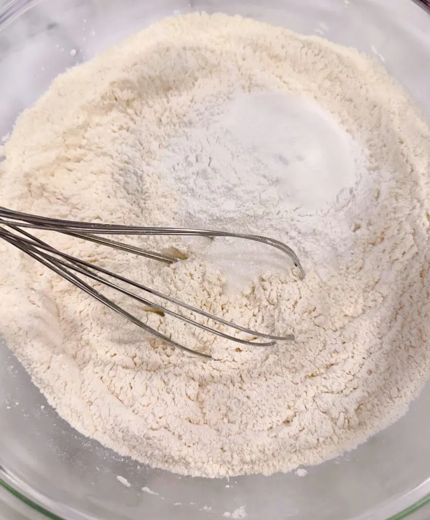 Whisking together dried pancake ingredients in a large bowl.