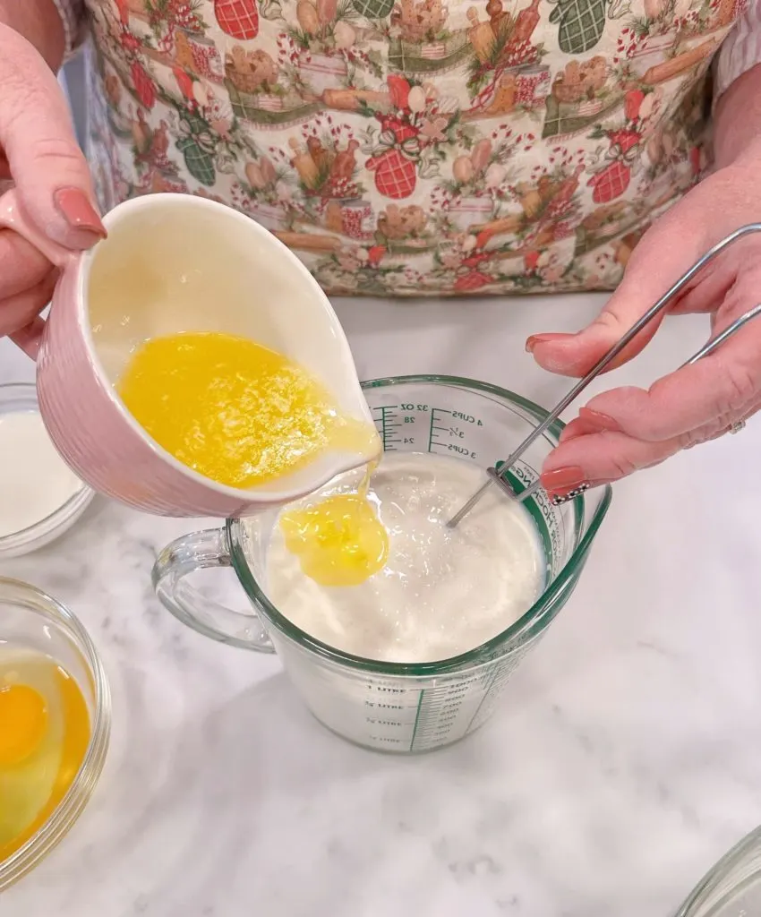 Adding melted butter to milk and egg mixture.