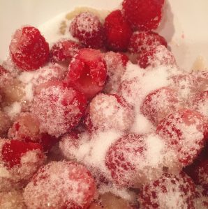 Bowl filled with fresh raspberries, apple juice, and sugar for raspberry filling