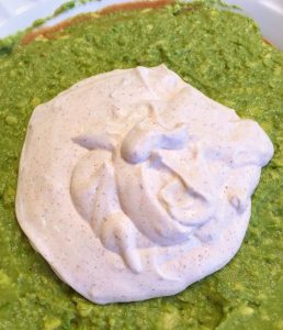 Sour cream taco seasoning mixture on top of guacamole