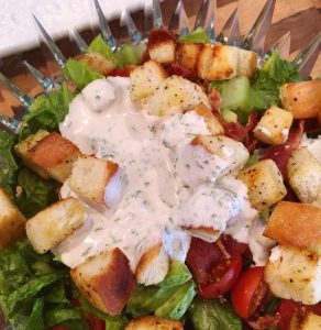 adding creamy dressing to salad