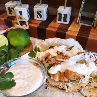 Easy Fish Tacos with Amazing Taco Sauce on a cutting board.