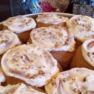 Full pan of baked carrot cake mix cinnamon rolls with frosting