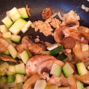 Adding minced garlic to veggies in skillet.