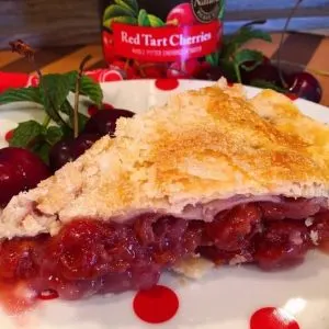 Slice of cherry pie on a red and white polka dot plate.