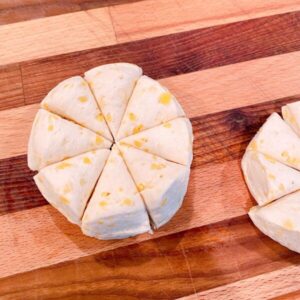 Canned biscuits on a cutting board cut into 8 pieces for top of casserole.