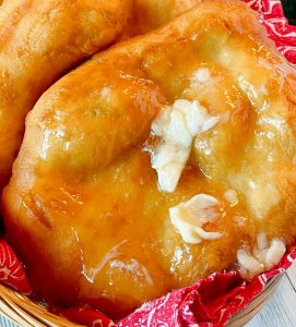 Four Indian Fry Breads in a basket with a red cloth napkin, fry bread with butter and honey.