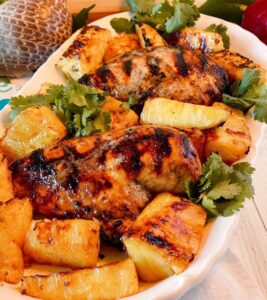 Close up photo of a platter filled Jerk chicken and grilled pineapple.