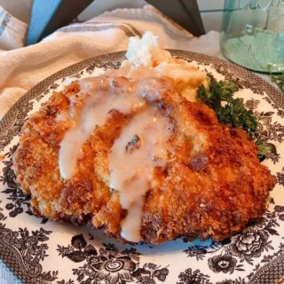 Chicken Fried Pork Steak on a plate with creamy gravy and mashed potatoes