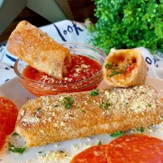 Fried Egg Rolls on a plate topped off with Parmesan Cheese and a side of marinara sauce.