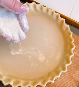 Sprinkling flour and sugar over the water in the pie crust