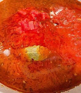 Pot filled with Goulash Ingredients including seasonings and tomato sauces.