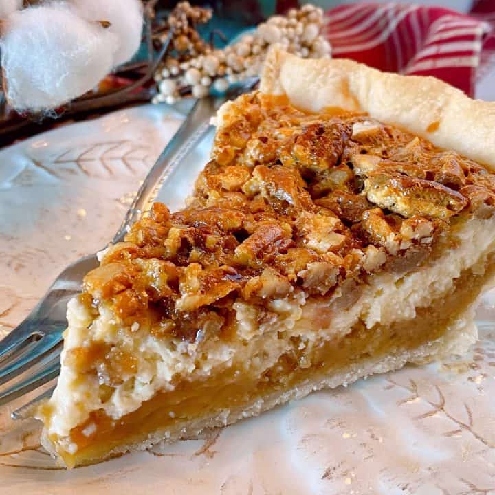 Close up of slice of Caramel Pecan Cheesecake Pie on a plate with a fork