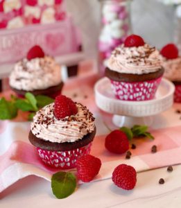 Cupcakes in a group with fresh raspberries and chocolate.