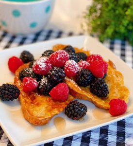 Croissant French Toast with fresh berries on a square white plate.